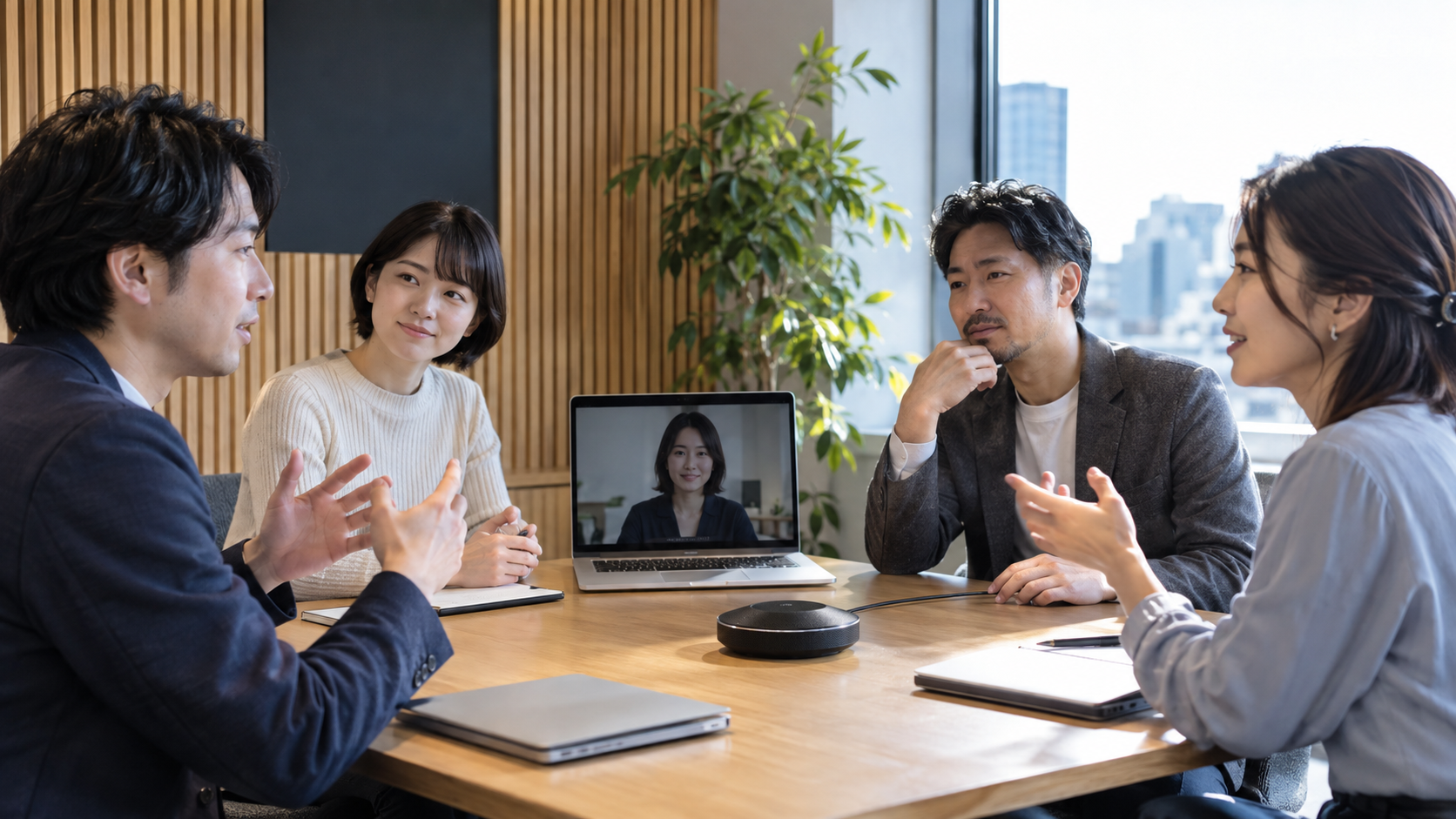 卓上マイクとノートPCを囲んで話すハイブリッド会議の参加者